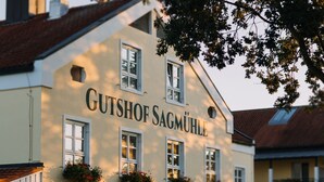 A building with the sign "Gutshof Sagemühle" and multiple windows with flower boxes. - Gutshof Sagmuehle (Bad Griesbach im Rottal)
