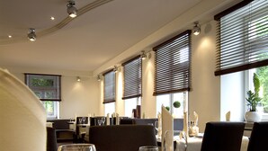 A dining area with a candle centerpiece, wine glasses, and a white tablecloth. - Hotel - Restaurant Roemer (Merzig)