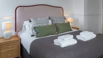 A neatly made bed with a striped headboard, two bedside lamps, and a bedside table with a lamp.