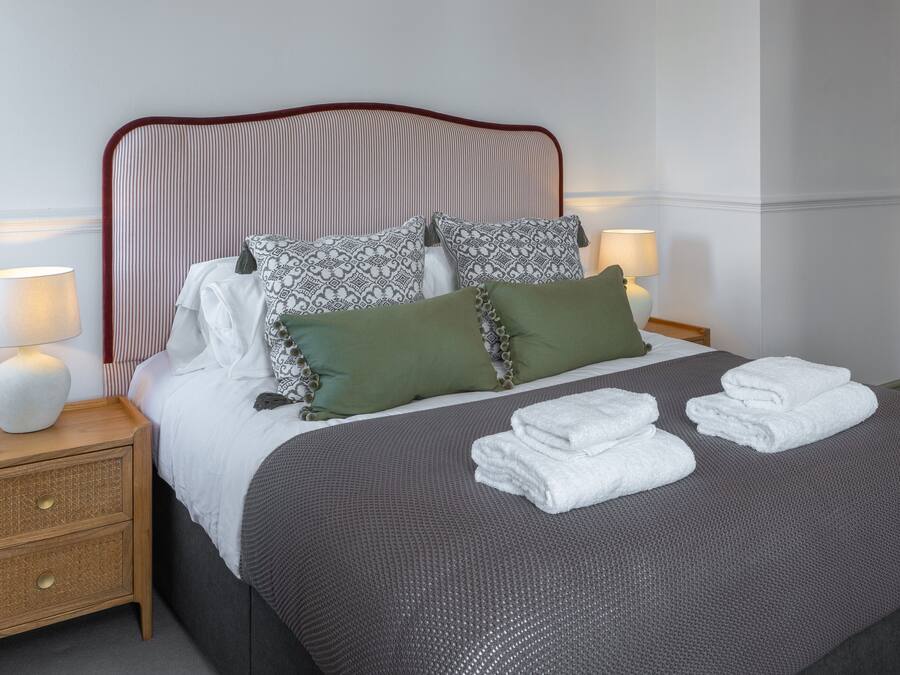 A neatly made bed with a striped headboard, two bedside lamps, and a bedside table with a lamp.