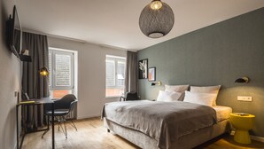 A modern bedroom with a large bed, a desk, and a chair.