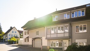 A two-story residential building with a garage door, a driveway, and a well-maintained lawn.