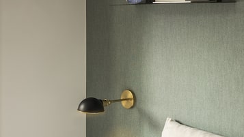 Una camera da letto con un letto, cuscini, una mensola a parete con oggetti decorativi e una lampada a parete.