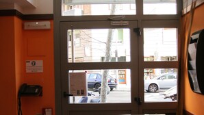 L’entrée d’un hôtel, avec une porte en verre, un comptoir d’accueil, un téléphone et une vue sur la rue.