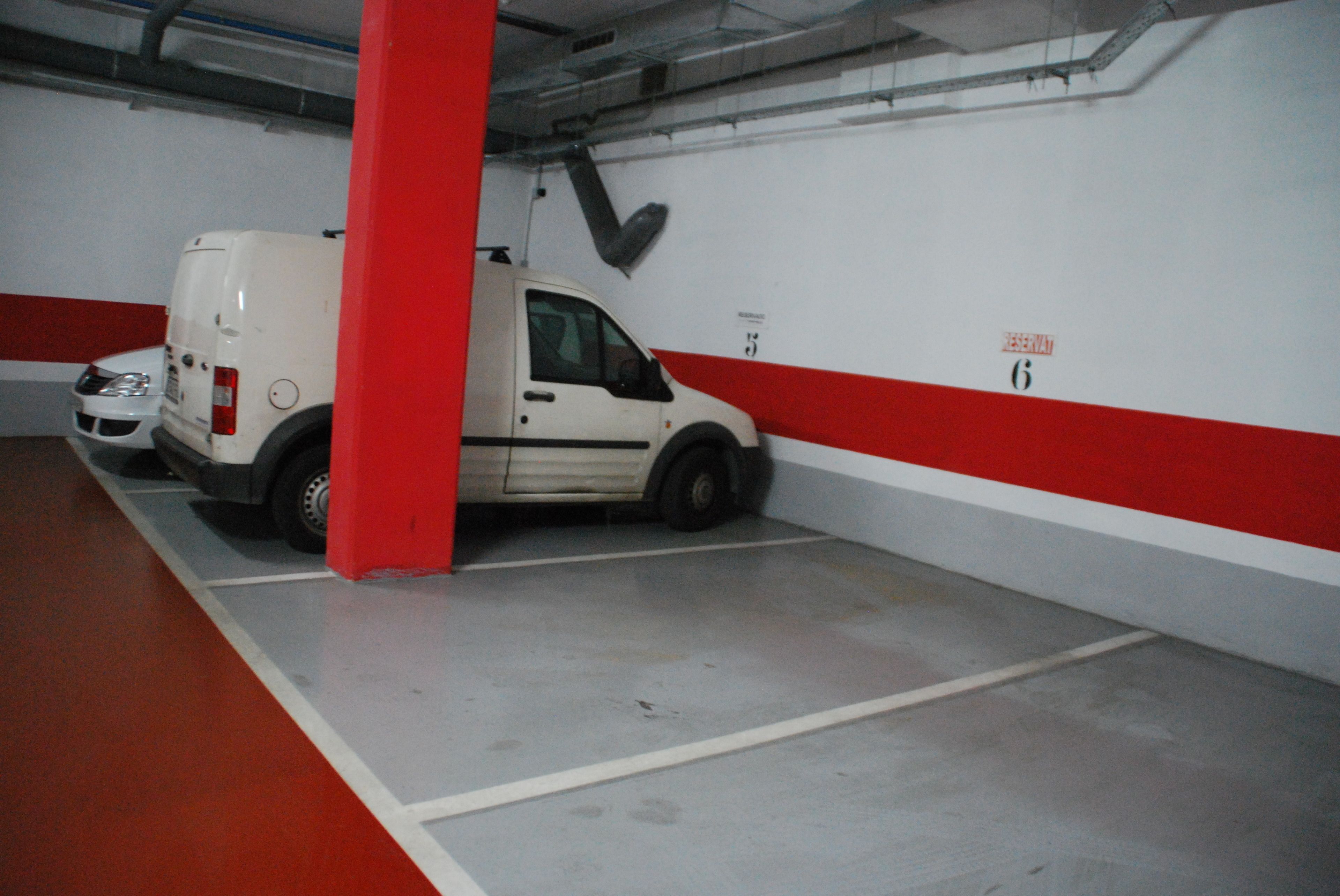 A parking garage with a white van parked in a space marked with the number 6.