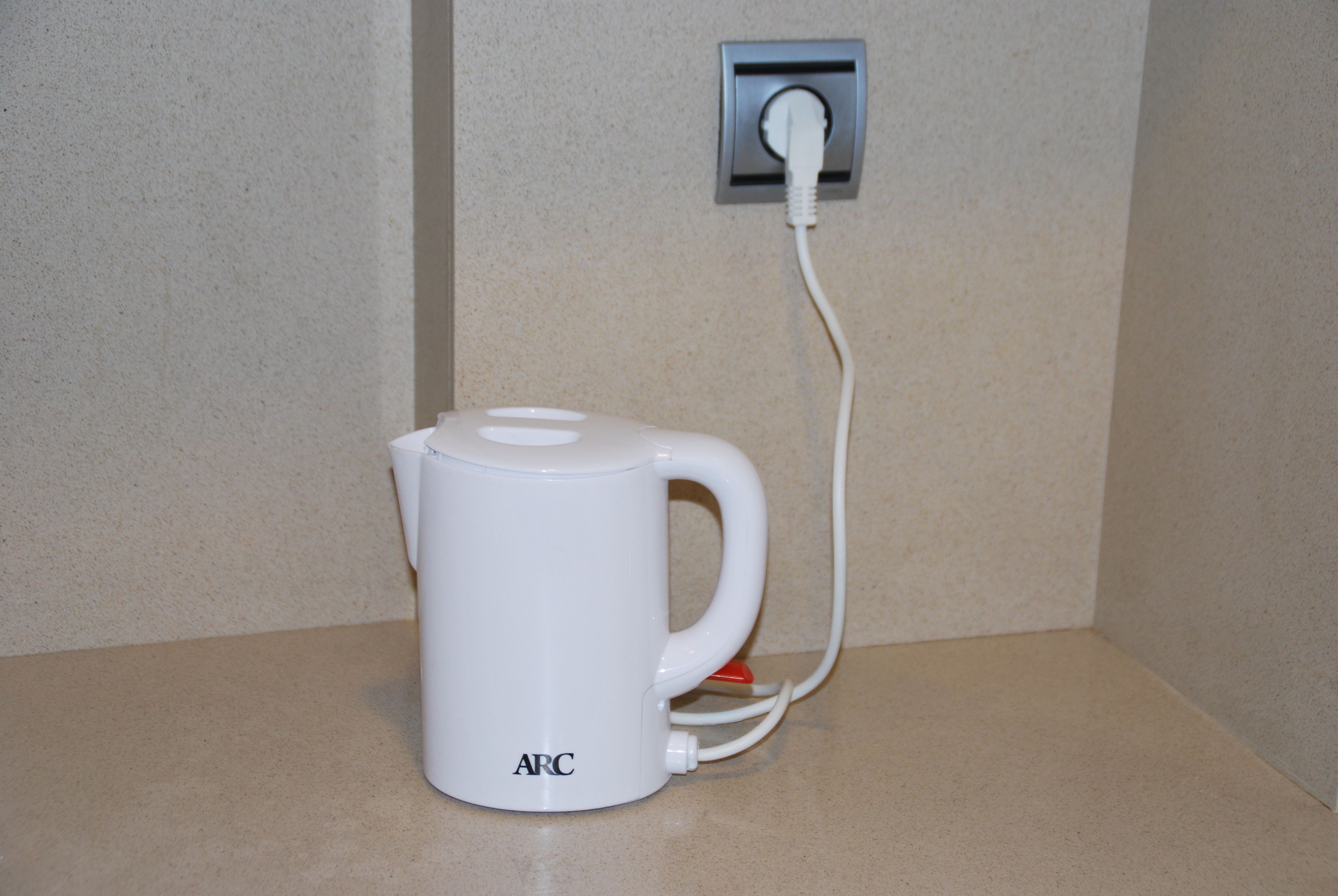 Una cafetera blanca con un cable conectado a un enchufe.
