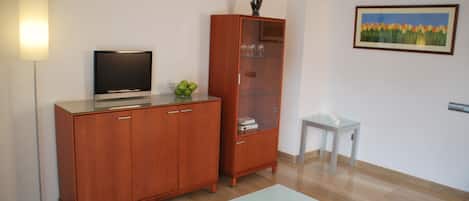 A modern room with a wooden cabinet, a glass table, and a framed painting on the wall.