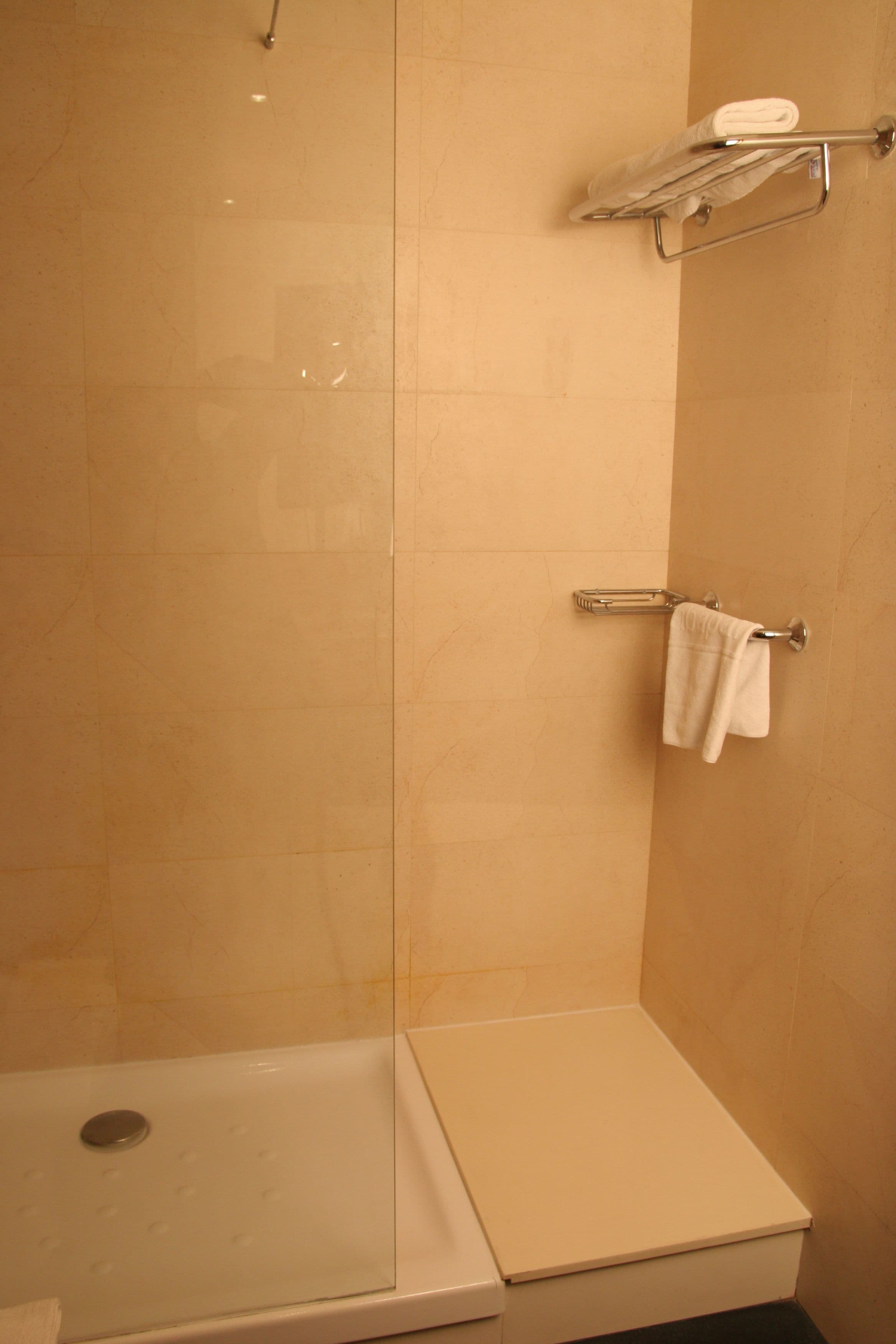 Un baño con ducha, inodoro y toallero.