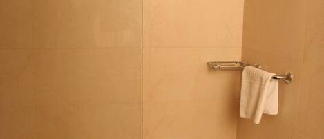 Un baño con ducha, inodoro y toallero.