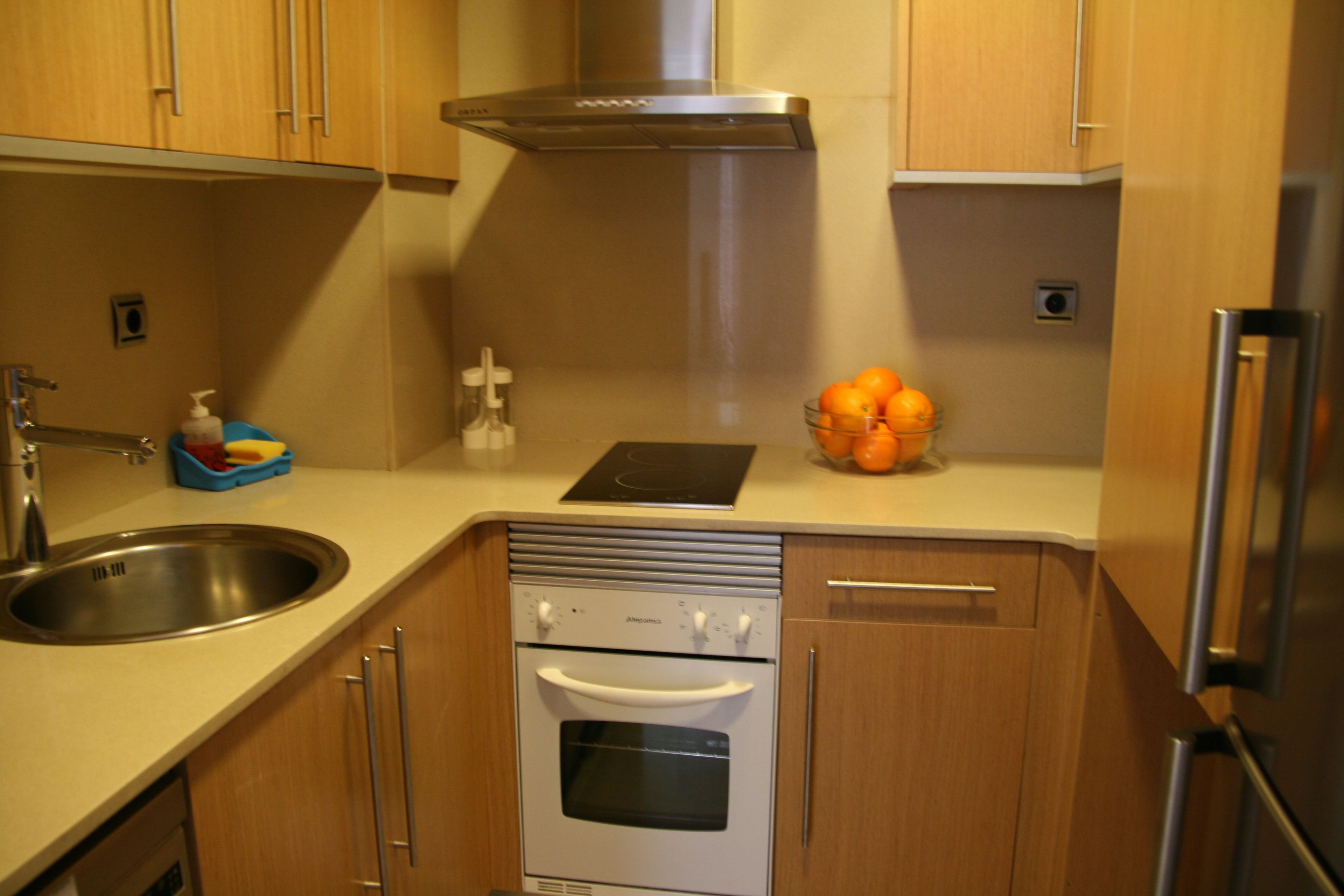 A modern kitchen with stainless steel appliances, wooden cabinets, and a built-in oven.