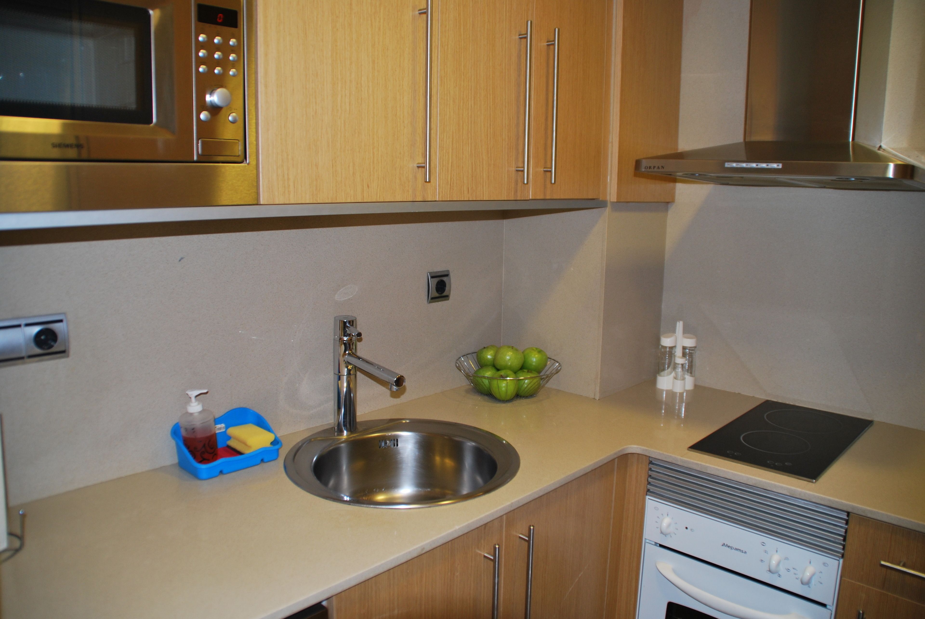 A kitchen with a stainless steel sink, a microwave, and a built-in oven.