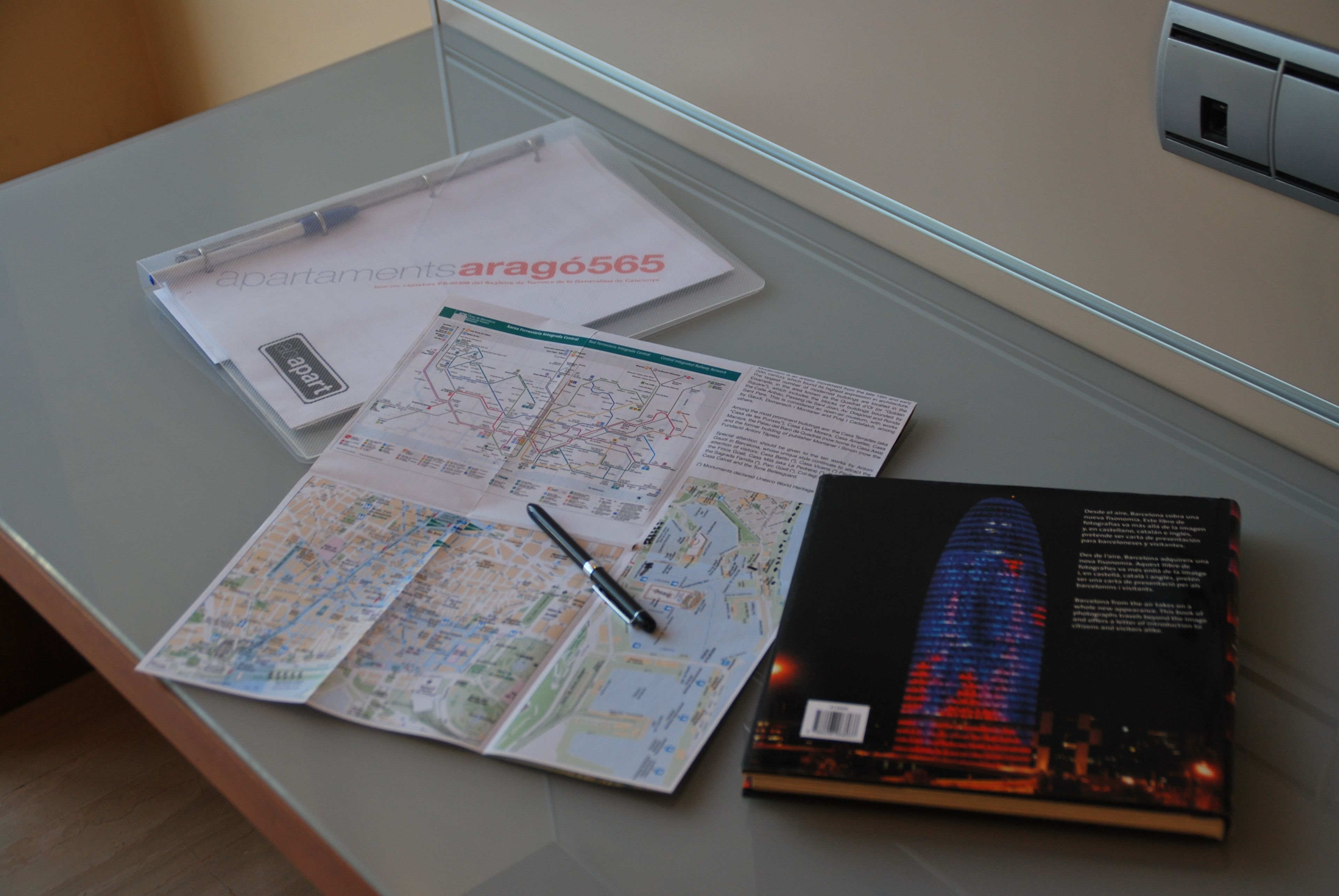 A desk with a map, a brochure, and a pen.