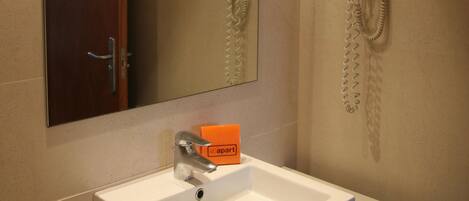 Un bagno con lavandino, specchio, portasciuga-asciugamani e asciugacapelli.