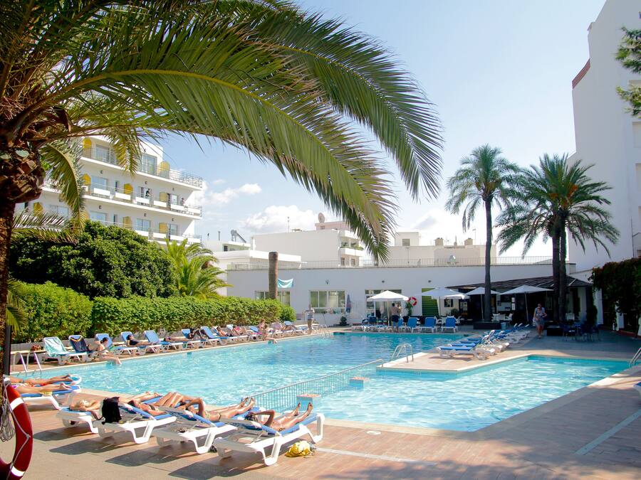 Una piscina al aire libre, sombrillas, sillones reclinables de piscina