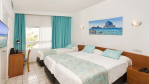 A hotel room with two beds, a desk, and a chair. There is a painting of a coastal landscape on the wall. - Hotel Tropical (Sant Antoni de Portmany)