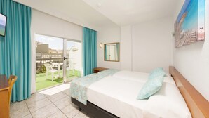 A hotel room with a bed, a desk, and a view of the outdoor area. - Hotel Tropical (Sant Antoni de Portmany)