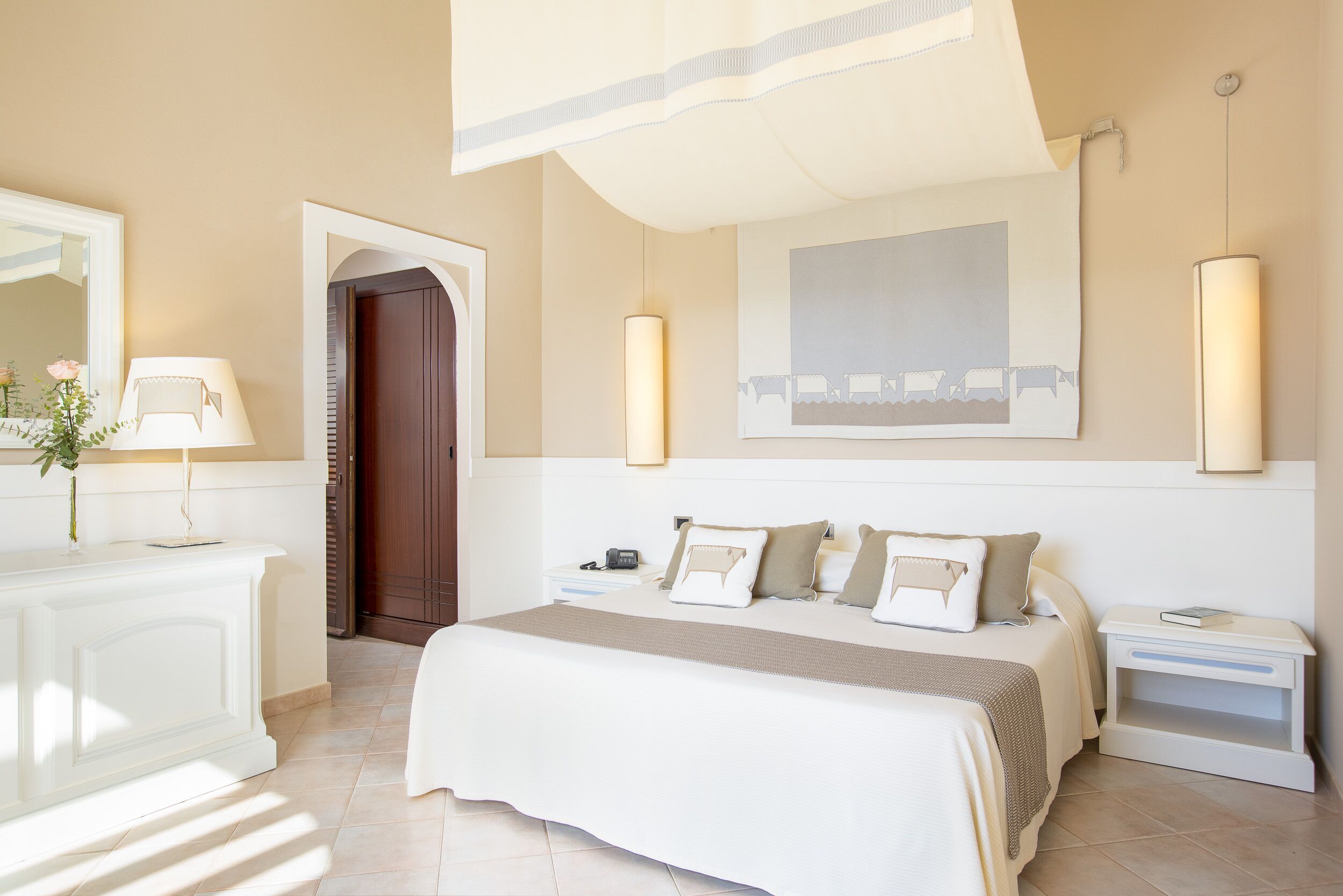 A bedroom with a bed, bedside tables, a nightstand, a mirror, and a door.