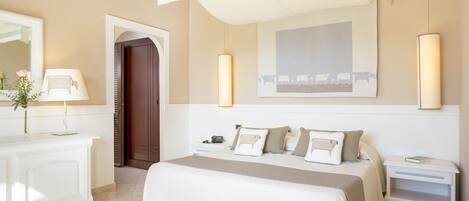 A bedroom with a bed, bedside tables, a nightstand, a mirror, and a door.