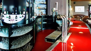 A bar area with a red floor, a circular bar counter, and shelves stocked with bottles.