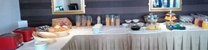 A buffet table with various food items and condiments, including baskets of bread, jars of spreads, and a fruit display. - Pitbauchlie House Hotel, Sure Hotel Collection by BW (Dunfermline)