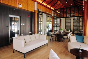 Een modern interieur met een houten plafond, een witte bank, een eettafel en uitzicht door een glazen deur.