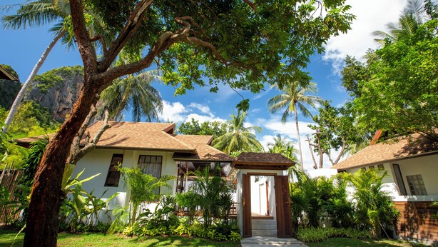 A tropical resort with a white building, palm trees, and a clear sky. - Railay Bay Resort and Spa (Krabi)