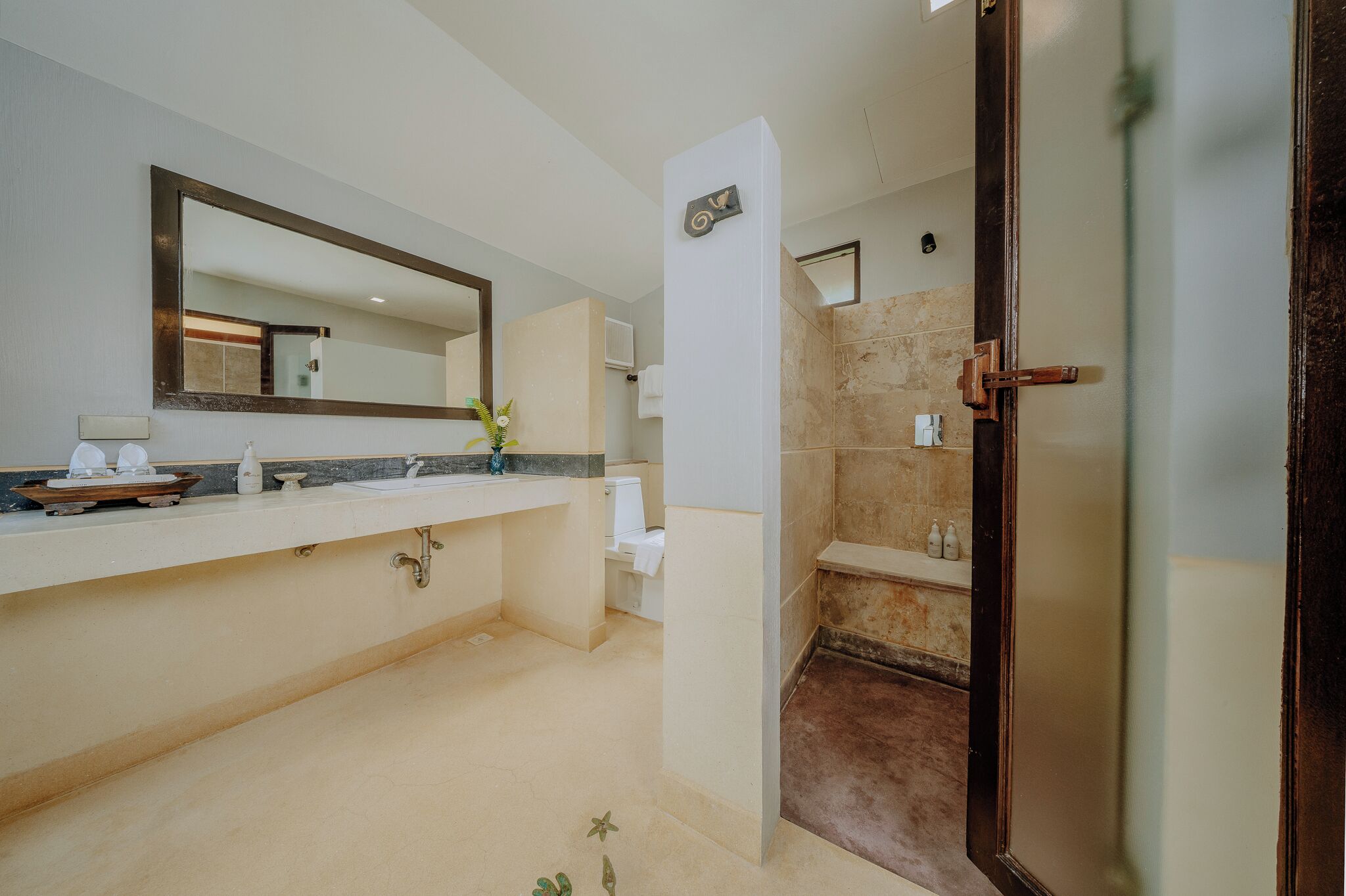 A bathroom with a large mirror, a sink, a toilet, and a shower area.