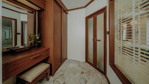 Un baño con tocador de madera, un banco, un espejo y una puerta con pulsador.