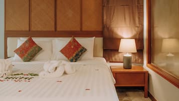 Een hotelkamer met een net opgemaakt bed, een bedlampje en een raam met gordijnen.