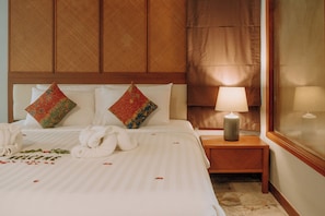 A hotel room with a neatly made bed, a bedside lamp, and a window with curtains.