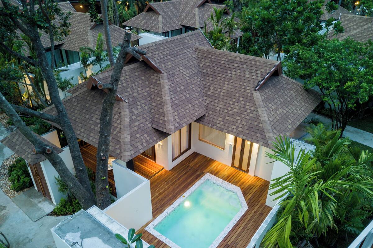A resort with multiple bungalow-style buildings, a central swimming pool, and lush tropical landscaping.