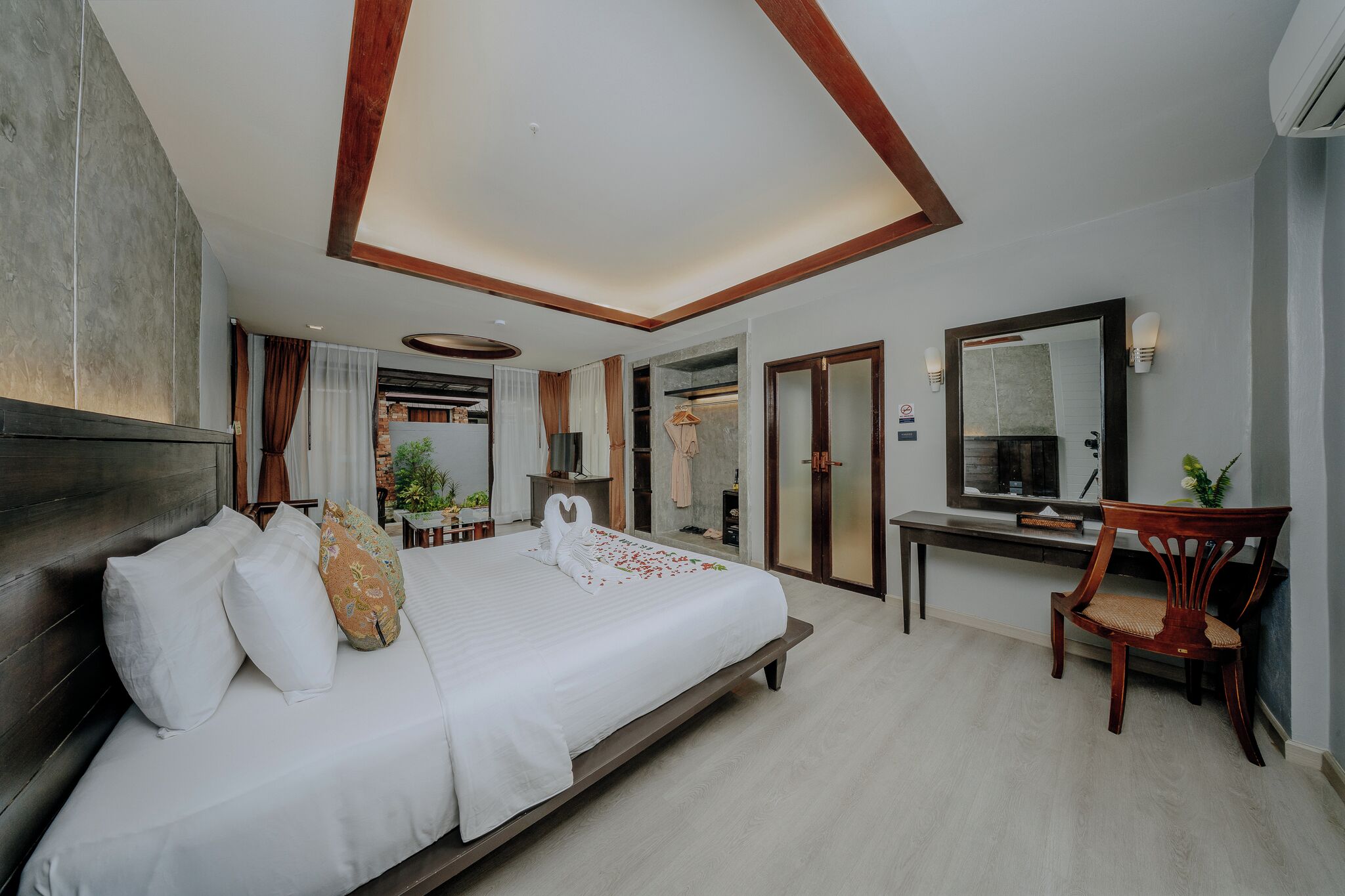 Habitación de hotel con una cama grande, un escritorio, una silla, un espejo y vistas al exterior.
