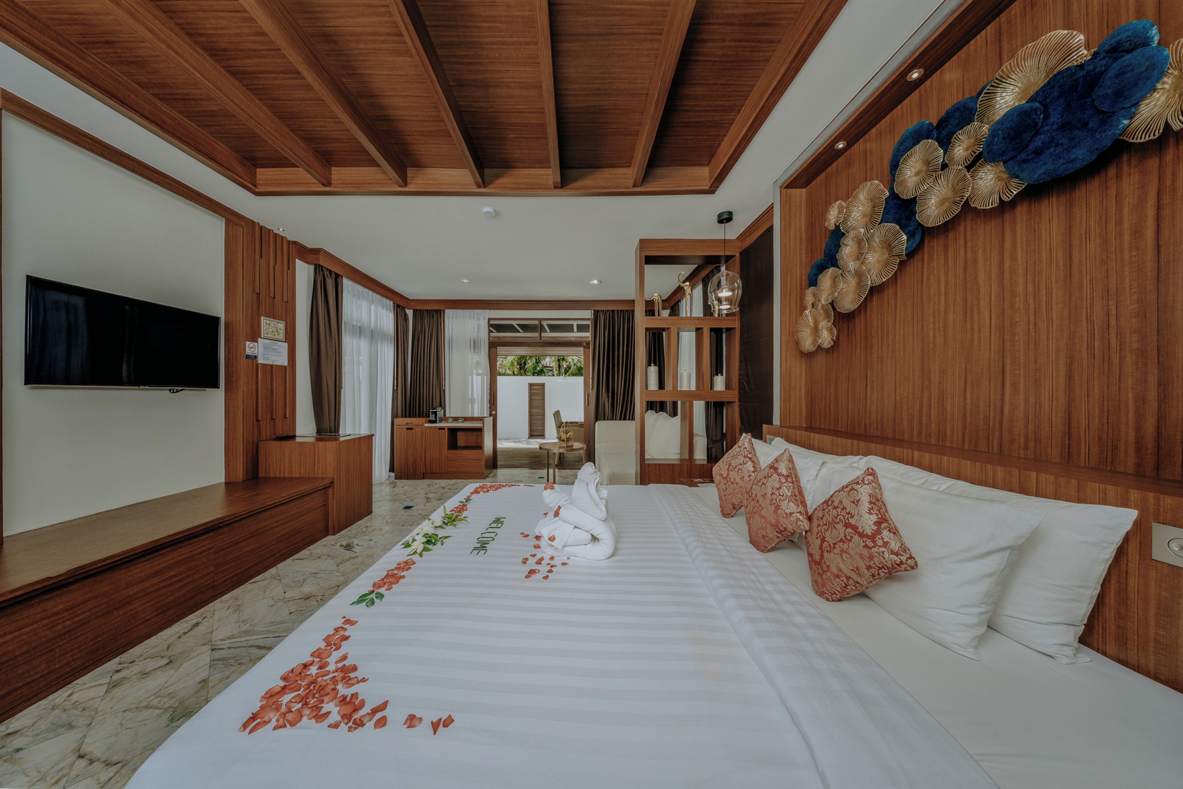 A hotel room with a bed, a TV, a wooden ceiling, and a view of the outside.