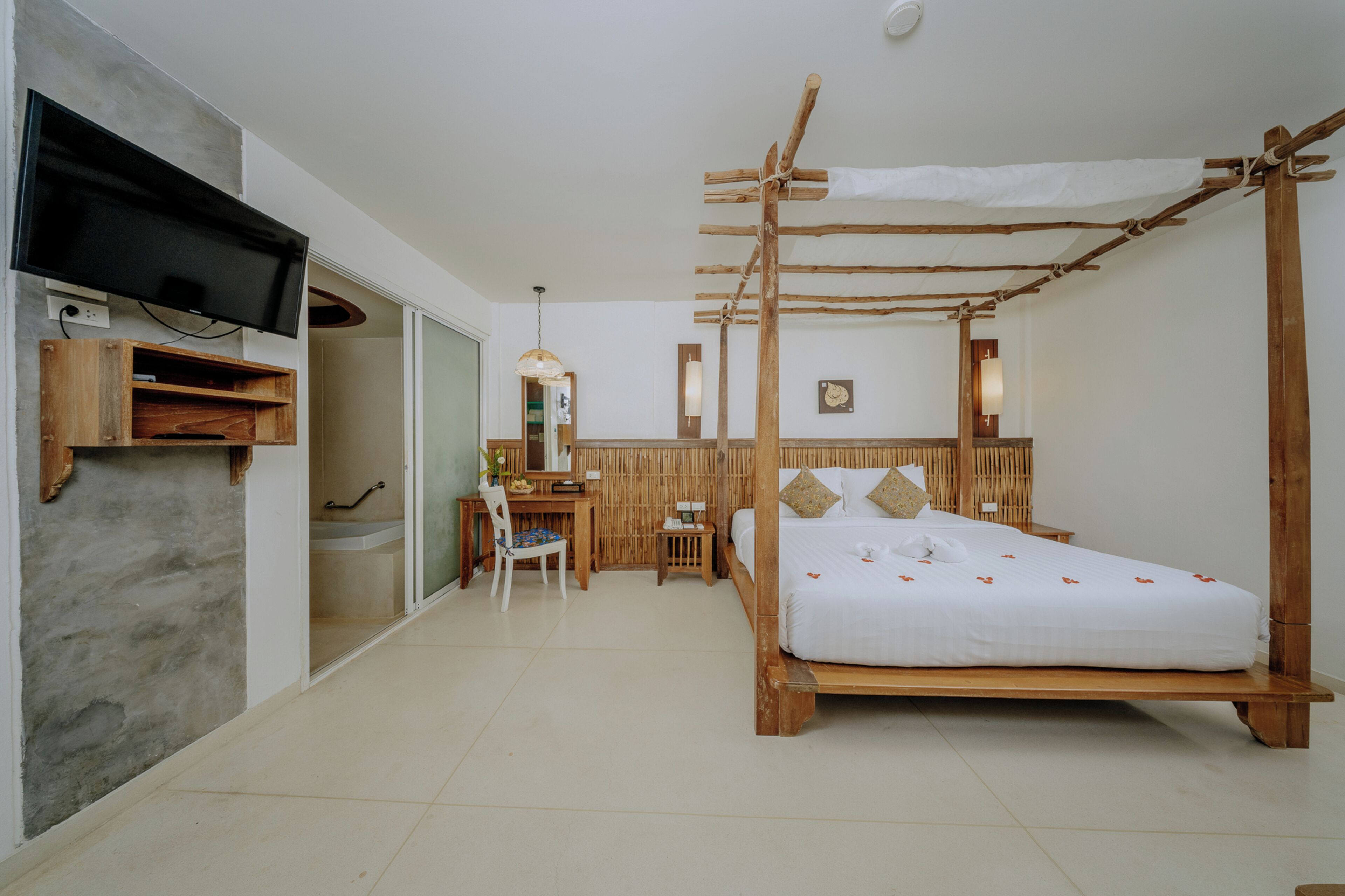 Una habitación con cama, escritorio, televisión y baño.