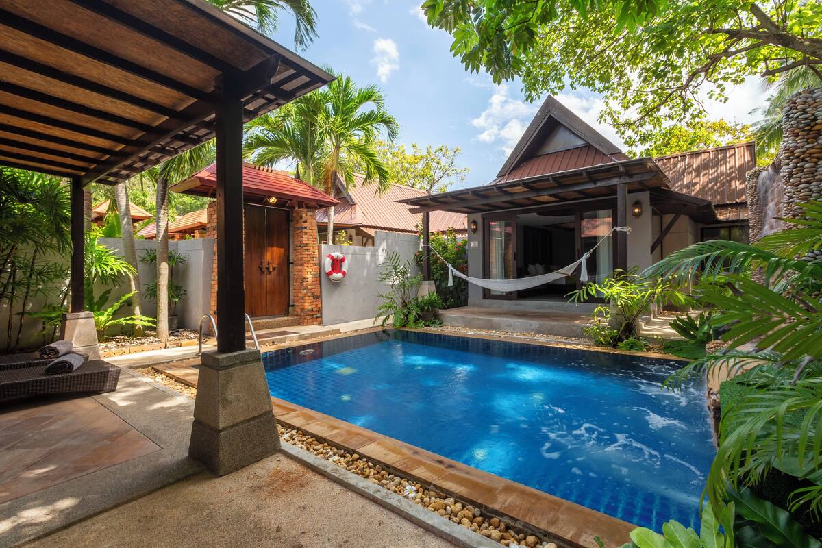 A swimming pool with a wooden deck and a hammock.