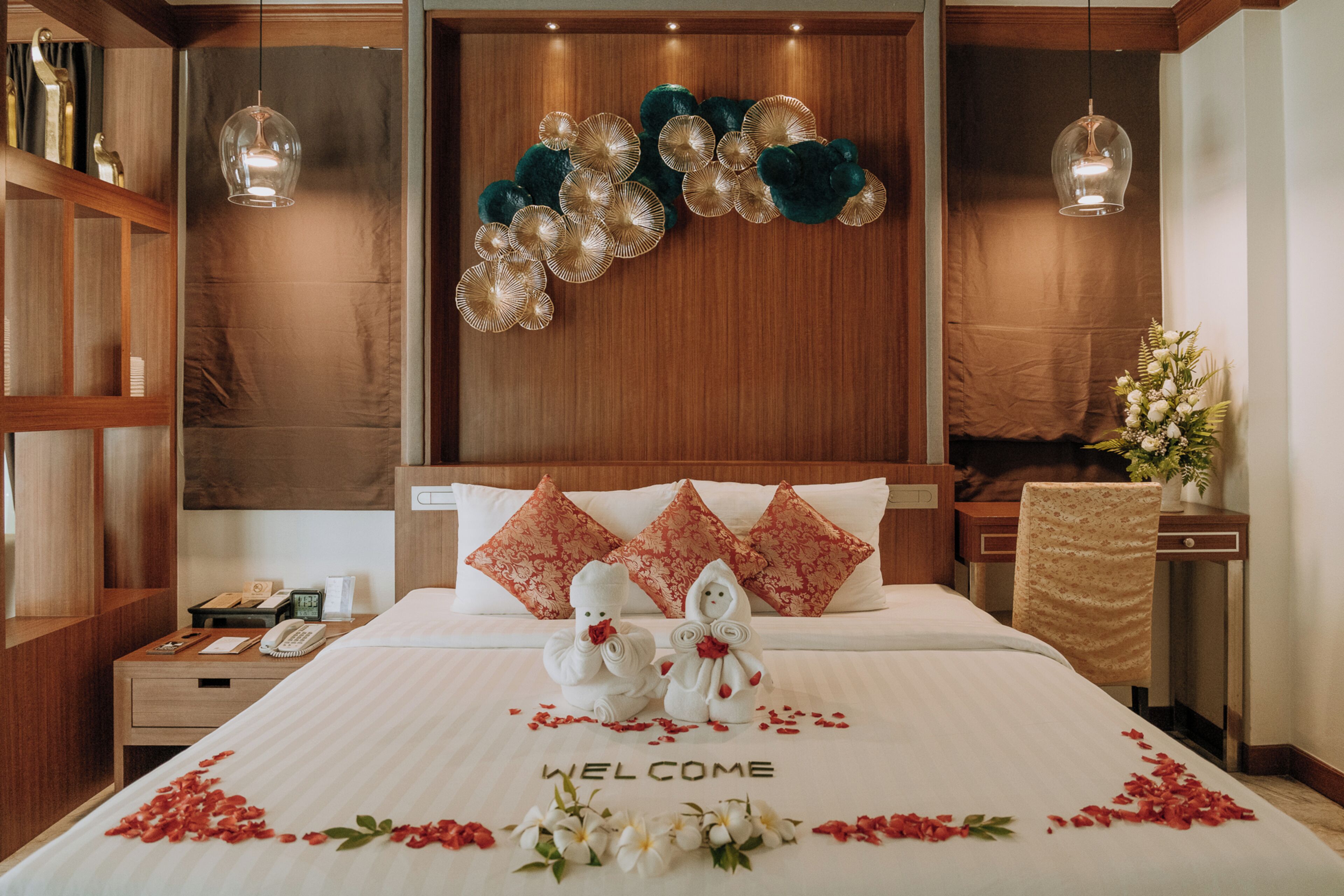 Habitación de hotel con cama, mesita de noche, teléfono, decoración de pared y un arreglo floral.
