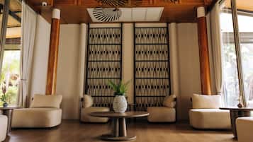 A modern interior with a wooden ceiling, a patterned wall, and a round table with a plant.