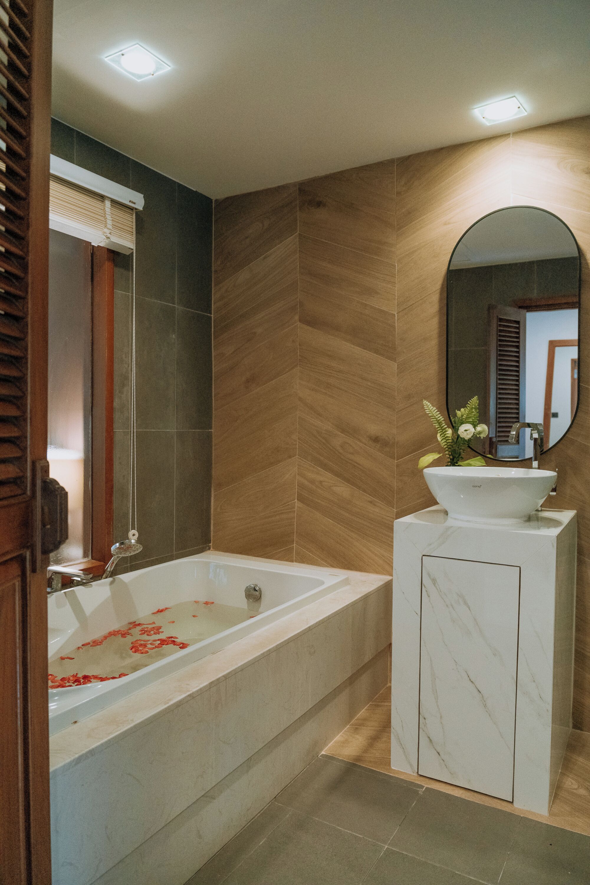 Un baño moderno con una bañera independiente, un tocador con espejo y una pared de madera.