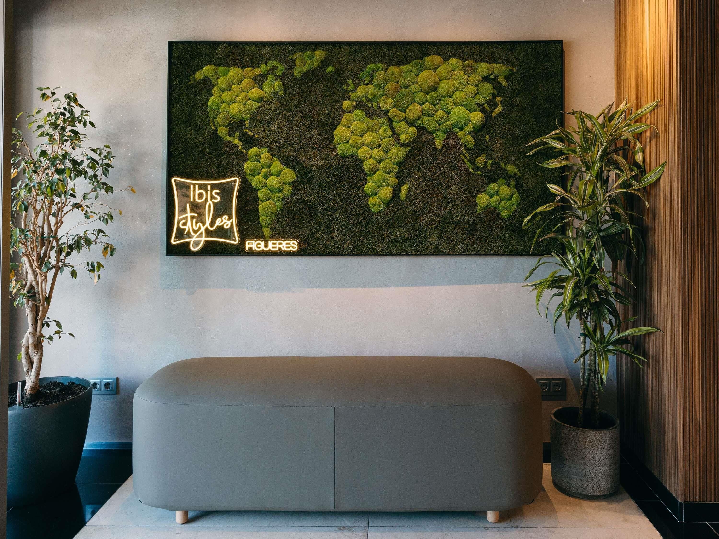 A modern interior with a world map mural, a neon sign, and a minimalist bench.