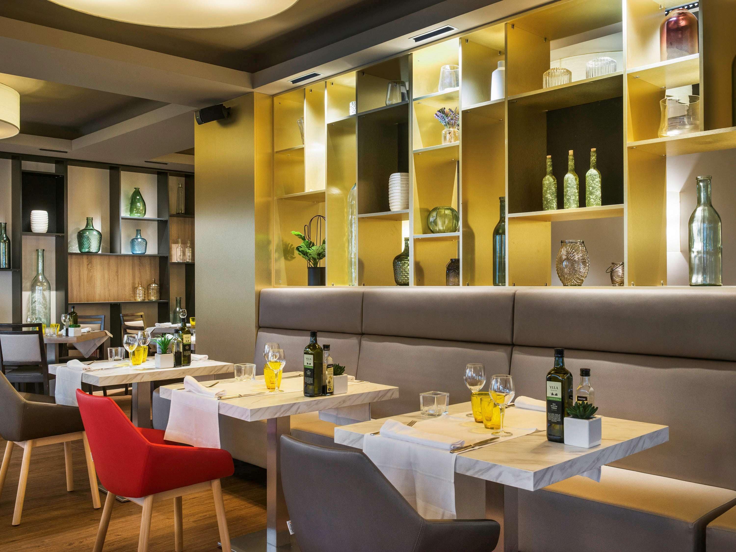 Ein Restaurantinneres mit mehreren Tischen, Stühlen und einer Auswahl an Gläsern und Flaschen auf Regalen.