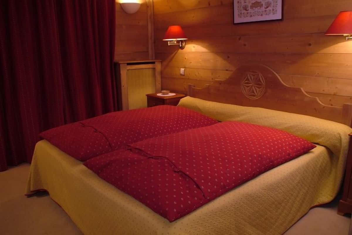 Une pièce en bois avec un lit, deux appliques murales et une petite table.