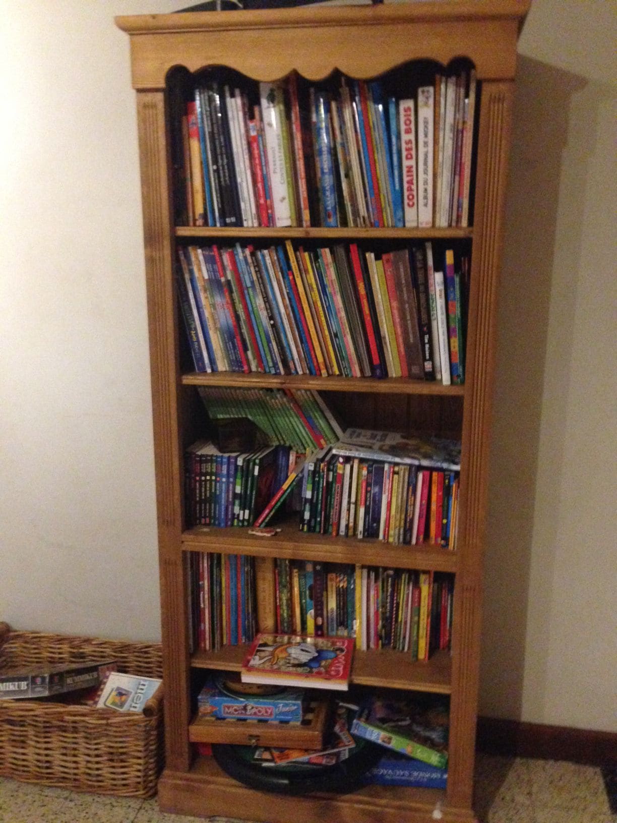 Une bibliothèque en bois remplie de divers livres et magazines.