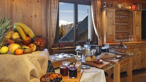 Interior de madera con una mesa de comedor dispuesta con frutas, bebidas y pan.