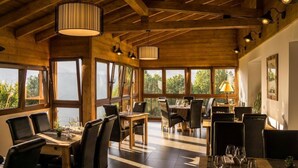 Comedor con vigas de madera, ventanas amplias y luminarias modernas.