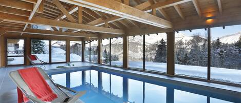 Una piscina interior con vistas despejadas a montañas nevadas a través de amplios ventanales.