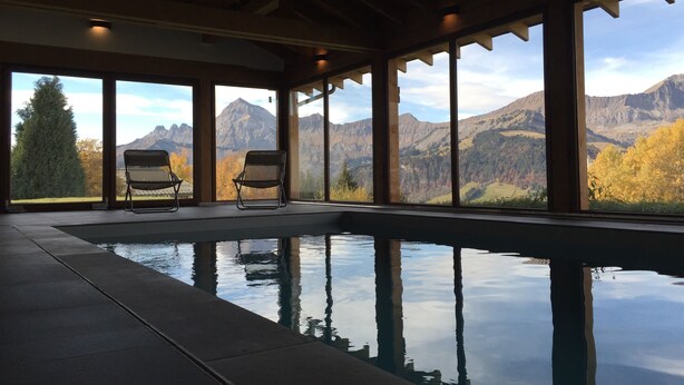 Una piscina interior con dos sillas y vistas a las montañas.