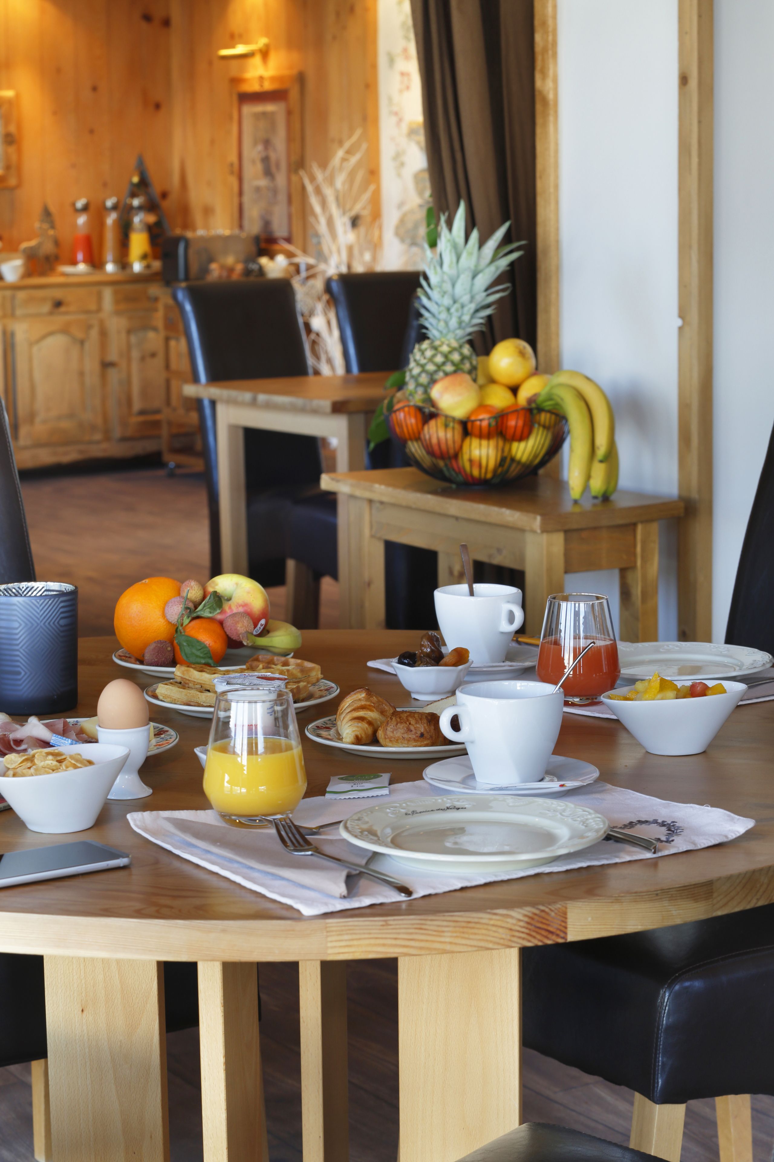 A breakfast table set with various dishes, including fruits, eggs, and pastries.