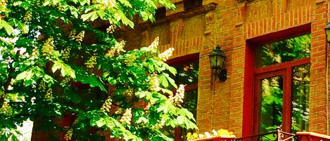 A brick building with large windows and a balcony with wrought iron railings.
