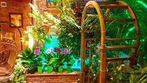 Un muro de ladrillo con una silla de madera y plantas en macetas.