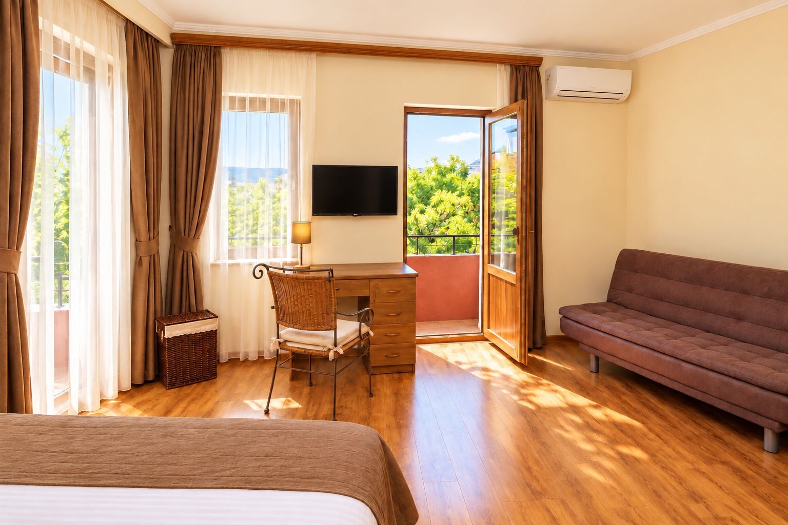 A hotel room with a bed, a desk with a chair, a sofa, and a TV.